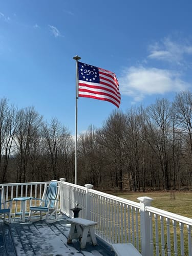 Customer's America 250™ Betsy Ross Flag flying on a tall flagpole from a deck on a sunny day.