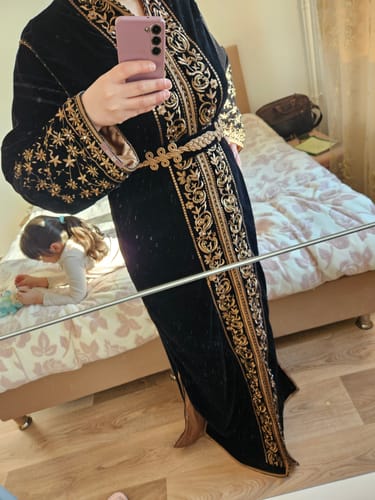 Reviewer takes a mirror selfie wearing the black velvet Ayla kaftan, highlighting the gold embroidery and matching belt.