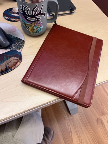 Customer's brown reMarkable Paper Pro Case closed on a desk, showing the elastic security band.