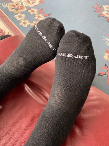 Close-up of a customer's feet wearing the black Quarter Socks while relaxing on a red surface.