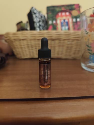 Customer's Onyx Reserve Dram Dropper, a small bottle with amber-colored oil, on a wooden surface.