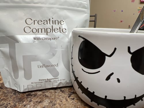 Customer's white pouch of Creatine Complete supplement sitting on a counter next to a large mug.