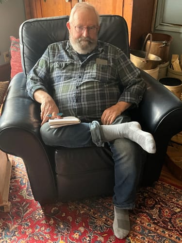 Customer sitting in a leather chair with legs crossed, wearing a pair of light grey Crew Socks.