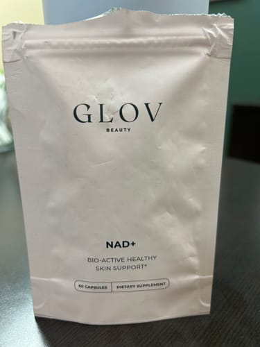 Customer's pink pouch of GLOV NAD+ Anti Aging Support Capsules sitting on a table.