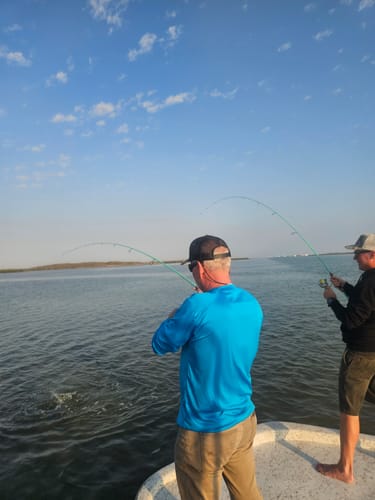 Customers fishing from a boat, their Waterloo Laguna Green Salinity rods bent with a catch.