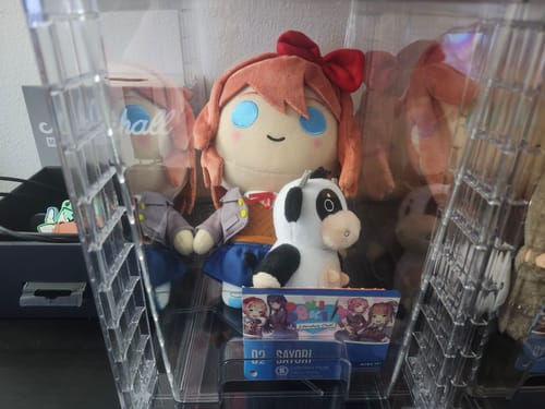 Customer's Sayori Collector's Plush in a clear display case, shown with the included Mr. Cow accessory.