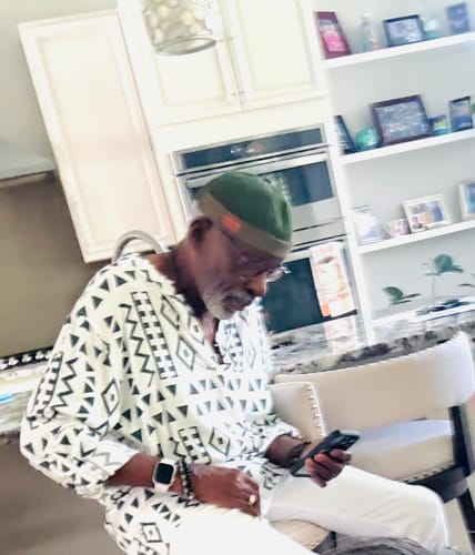 Reviewer sitting indoors wearing a green brimless docker beanie hat while looking at a phone.