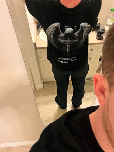 Reviewer in a mirror selfie showing the back graphic of the black Wings of War oversized t-shirt.