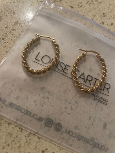 Customer's gold, twisted Missoma Earrings shown on their packaging after unboxing.