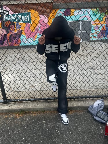 Reviewer wearing the full black VISIONZ SWEATS outfit, posing outdoors with the hood up.