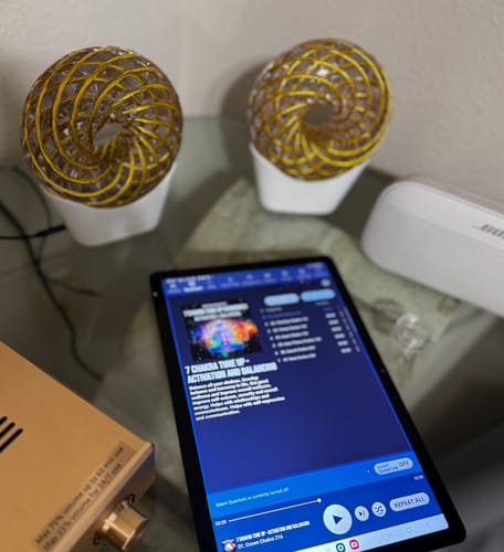 Reviewer's Qi Coil Max system with two gold coils and a console, shown on a table with the control app open on a tablet.