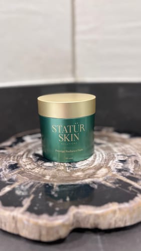 Customer's Prestige Radiance Pads, from the Restoration Ritual Set, in a green tub with a gold lid on a counter.