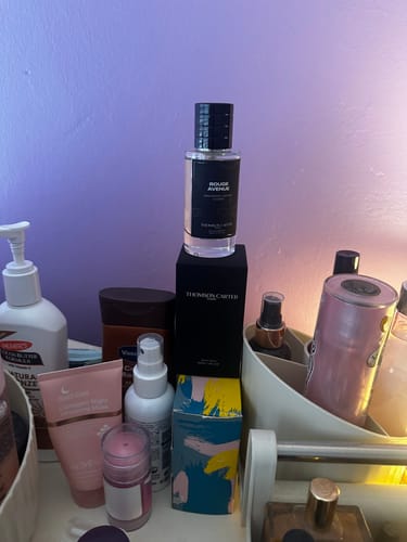 Customer's Smoke & Mirrors Eau de Parfum bottle on its box, among other products on a cluttered vanity.