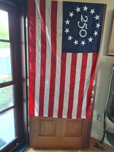 Reviewer's America 250 Betsy Ross flag hanging on a wooden front door.