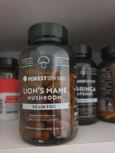 Customer's bottle of Forest Super Foods Lion's Mane Mushroom capsules on a white shelf.
