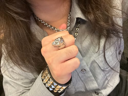Close-up of a customer wearing the 8MM MINI ARIES CHAIN around their neck, holding it with their hand.