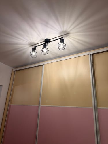 Clientul arată lustra neagră ONZY cu 3 spoturi, montată și aprinsă pe tavanul unei camere.