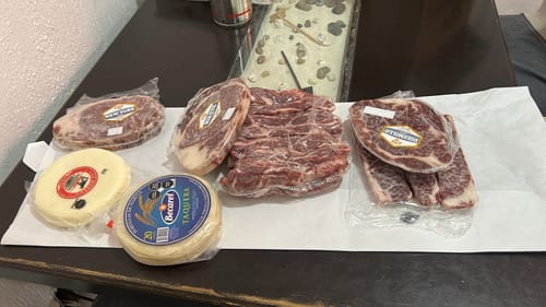 Cliente mostrando los productos del Kit Carne Asada en sus empaques originales sobre una mesa.