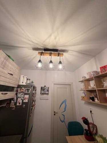 Recenzent arată lustra sa Wood Style instalată pe tavan. Cele trei becuri sunt aprinse, iluminând încăperea.