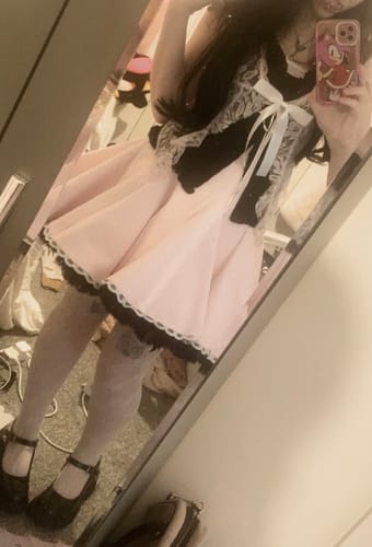 Reviewer in a mirror selfie wearing the pink Dolly Polka Dot Dress, styled with a black lace top, showing the flared skirt.