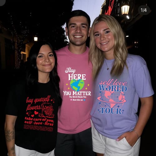 Reviewer's photo showing three people, with the person in the middle wearing the pink Smile | Stay Here Shirt.