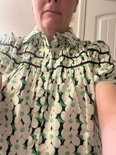 Reviewer's close-up of the floral Retro Bloom Button Blouse, showing the pintuck detailing and contrast piping.