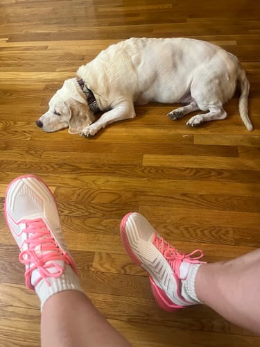 Reviewer's perspective looking down at their white and pink ULTRASHOT 4 shoes on a wood floor.