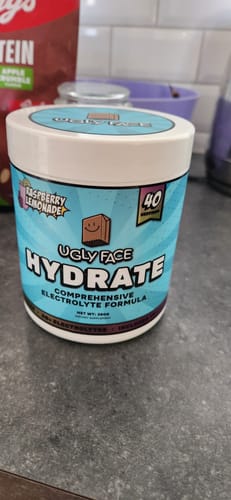 Reviewer's tub of UGLYFACE HYDRATE in Raspberry Lemonade flavor sitting on a kitchen counter.