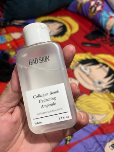 Reviewer holding the translucent bottle of Bad Skin Korean Collagen Bomb Hydrating Ampoule in their hand.