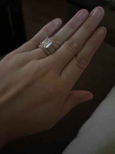 A reviewer's hand wearing the Emerald Cut CZ Silicone Ring Set, showing the large clear stone on the silicone band.