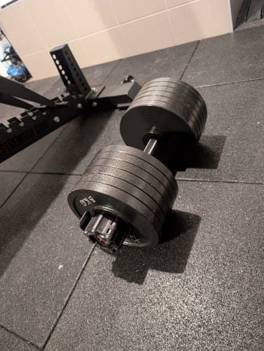 Reviewer's Granuflex Rubber Flooring tiles in a home gym, with a heavy dumbbell resting on top.