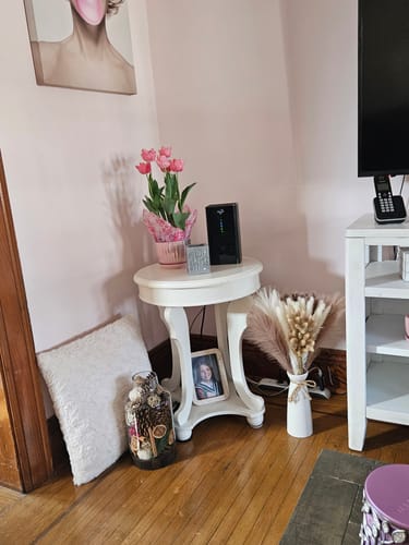 Customer's cozy room corner with a white side table, pink tulips, and decor.