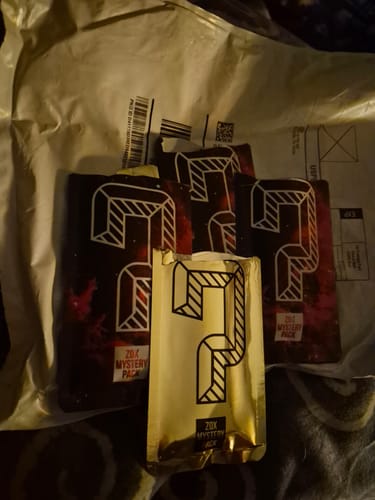 Customer's ZOX Mystery Packs, showing one gold pack in front of several dark packs on a mailer.