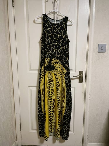 Customer's black sleeveless maxi dress with a large yellow polka-dot graphic hanging on a door.