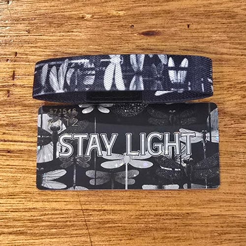 Customer's black and white "Stay Light" bracelet and matching card, both featuring a dragonfly pattern.
