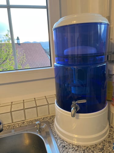 Der blaue PI®PRIME K8 Wasserfilter eines Kunden auf einer Küchentheke neben dem Fenster.