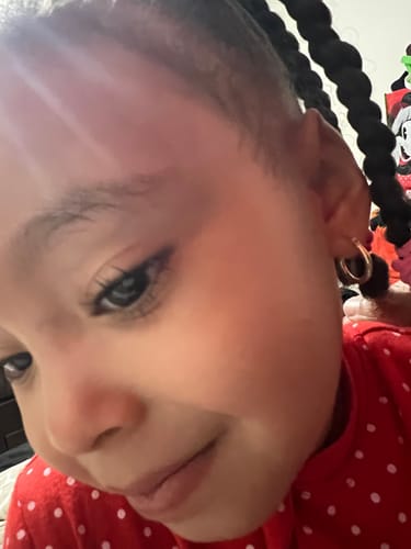Customer's close-up of a child wearing the 14k Small Hoop Earring in her ear.