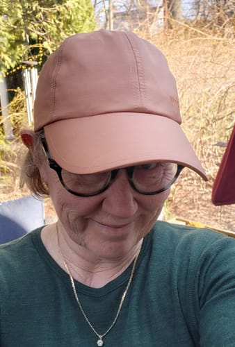 A reviewer wearing the salmon-colored Frankie Baseball Hat outdoors, showing its fit and neutral tone.