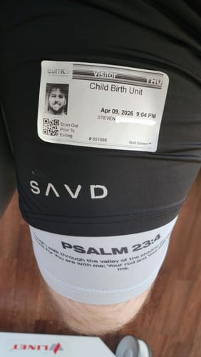 Customer's Psalm 23:4 Performance Shorts shown with a Child Birth Unit visitor badge in a hospital setting.