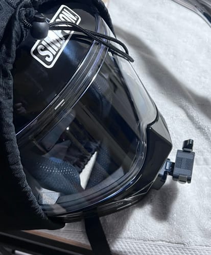 Customer's side view of the camera mount attached to the chin bar of a black Simpson helmet.