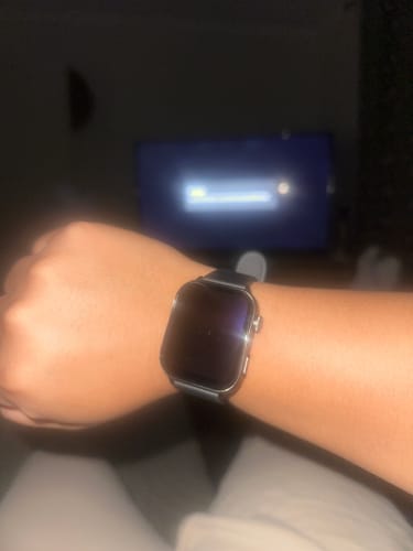 Close-up of a customer's wrist wearing a smartwatch with a dark screen in a dim room.