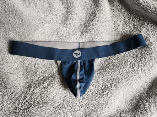 A customer's navy blue Nylon Strapless Jock laid flat on a grey, fluffy surface.