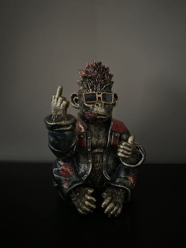 Kundens rockeape-figur i antikkgull som sitter med solbriller på og gir fingeren.