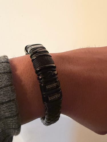 A close-up of a reviewer wearing the personalized black bracelet on their wrist, showing engraved names.