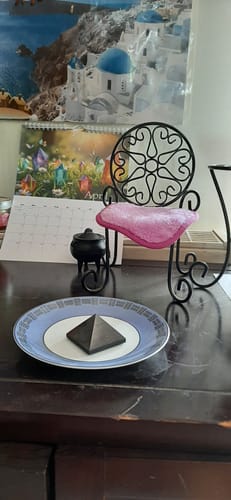 Cliente montrant la pyramide de Shungite posée sur une assiette sur une table de chevet.