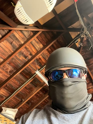 Customer wearing the black Switchback Reversible Helmet, sunglasses, and a face covering indoors.