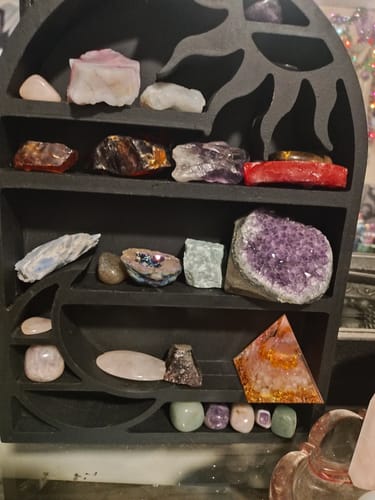 Customer's crystal collection on a black decorative shelf, featuring items from their AuraBloom Subscription Box.