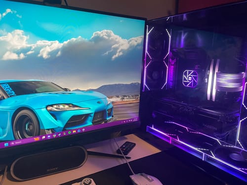 Customer's QuickEntry87 digital wallpaper of a blue sports car displayed on a monitor next to a glowing PC.