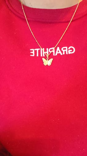 Reviewer wearing the gold Patience & Hope butterfly necklace over a red sweatshirt.