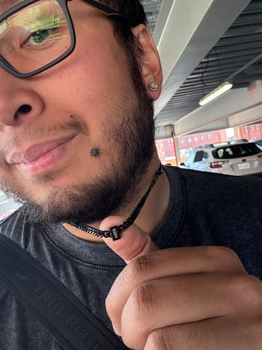 Customer wearing the black Legacy Necklace, holding up a personalized bead for a close-up view.